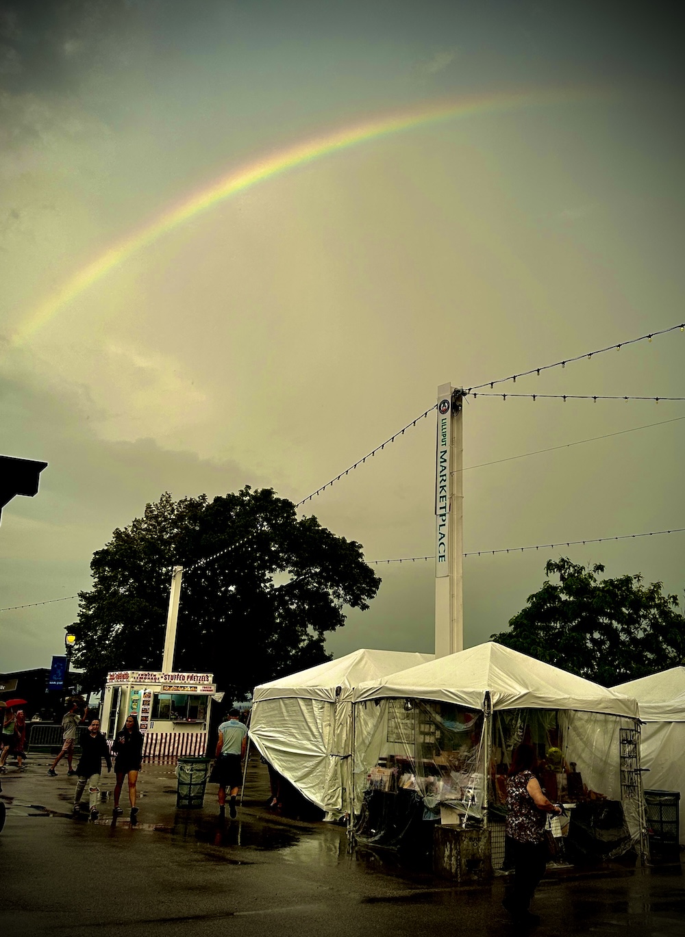 A rainbow is seen at Milwaukee Irish Fest 2024, arcing above the Reflective Jewelry booth.